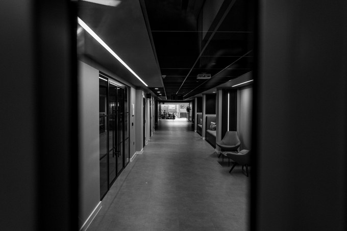 A lit corridor with strip lighting overhead and an empty armchair set against the wall.