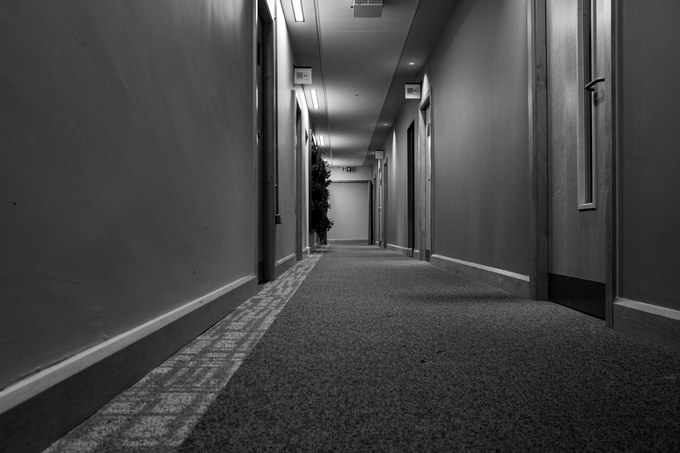 A low view along an empty carpeted corridor, doors closed on both sides.
