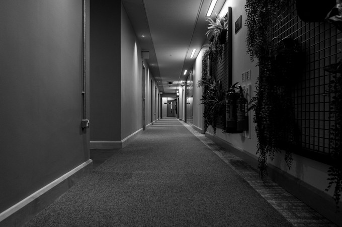 Fire extinguishers mounted on a planted corridor wall, the corridor empty in both directions.