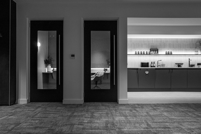 Two glazed meeting room doors beside a tea point, the counter set and unused.