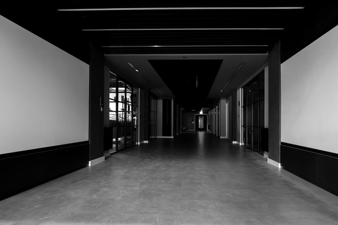 A wide dark corridor running between glazed offices, empty end to end.
