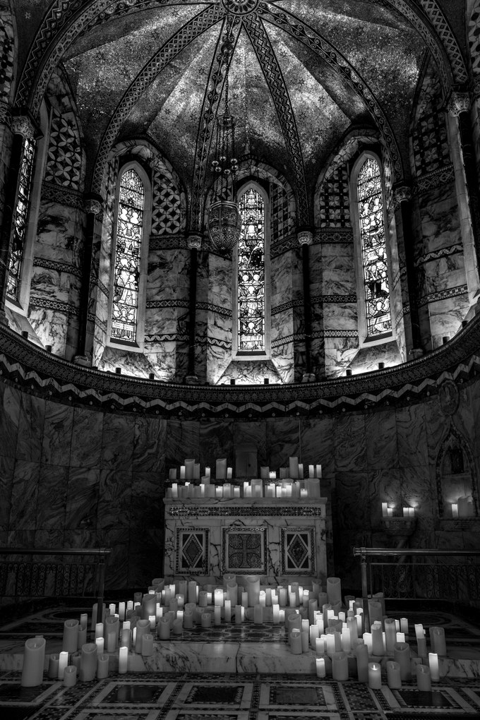 The interior of the Fitzrovia Chapel, its marble apse and mosaic vault above an altar, candles massed across the floor.