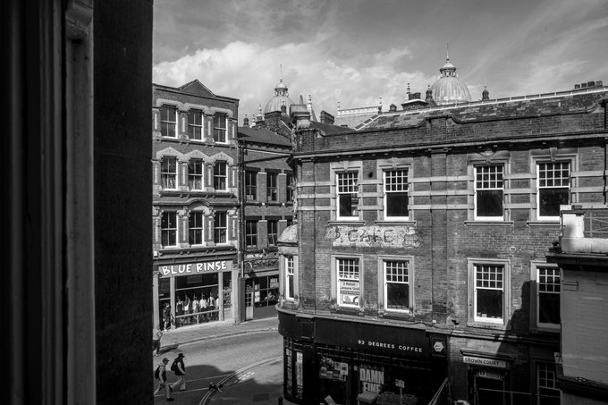 The view from a window of Colours May Vary in the Leeds Corn Exchange, across to Blue Rinse and 92 Degrees Coffee, a faded painted CAFE sign on the brick and domes on the skyline.