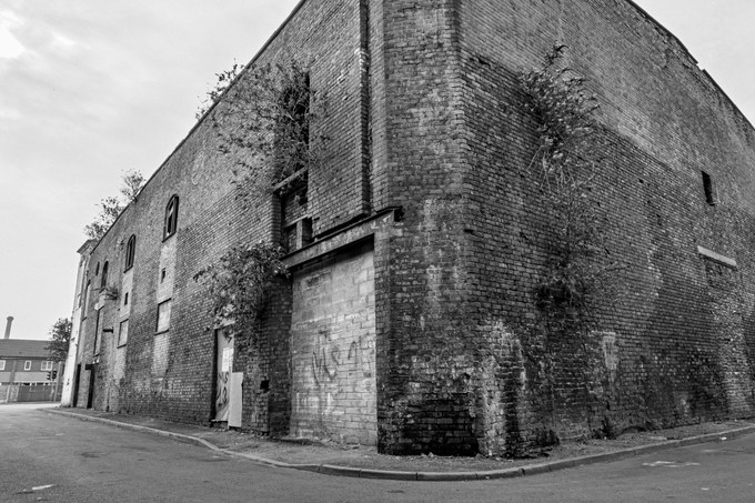 The blank brick rear elevation of the New Osborne at a street corner, a loading door at the base.