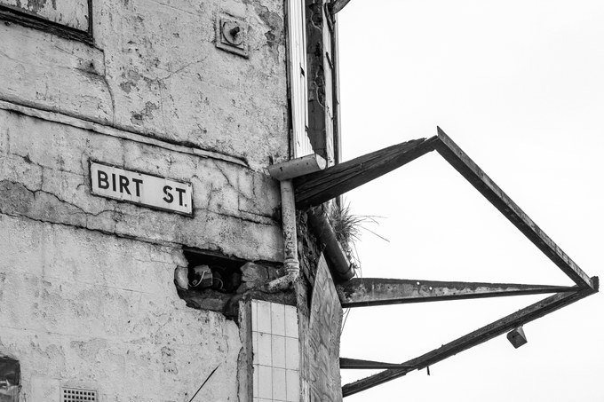 A Birt Street sign on the rendered corner of the New Osborne, a broken canopy jutting out above.