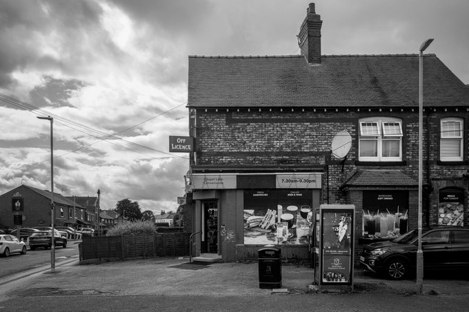 Chapel Lane Convenience, an off licence with a projecting sign and opening hours of 7.30am to 9.30pm painted on the fascia.